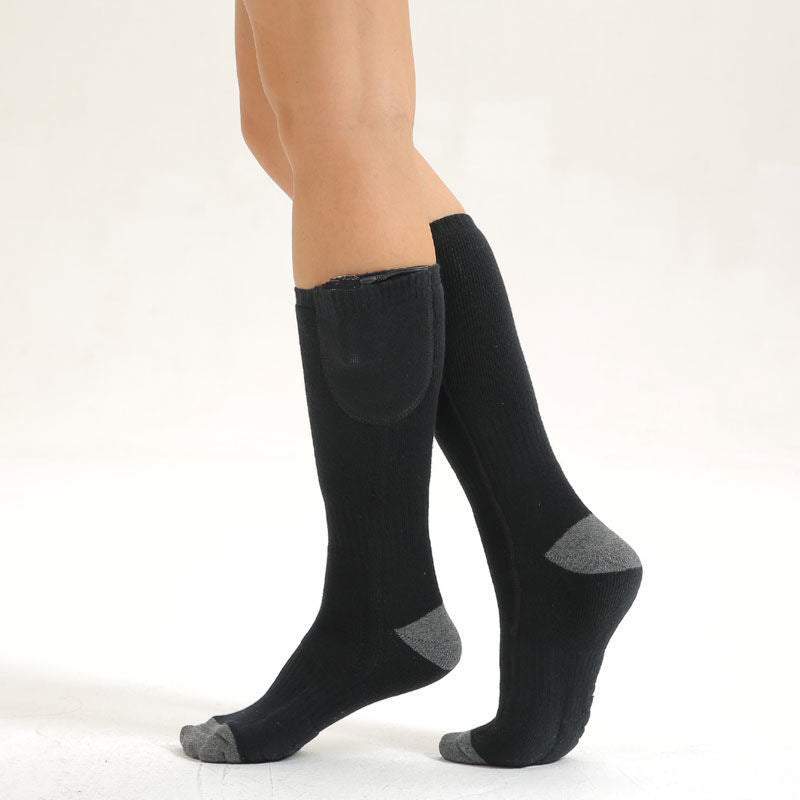 Black knee-high heated socks with gray accents worn by a person on a white background