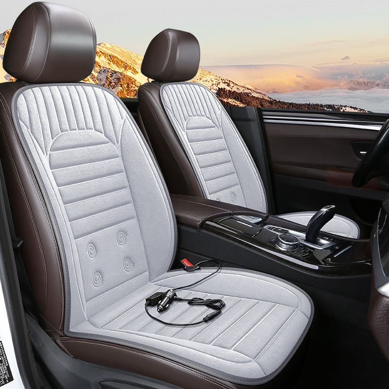 Car interior with heated seat covers and power adapter, mountain landscape outside.